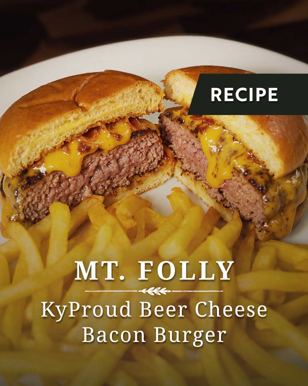 A juicy burger sliced in half on a plate with french fries. Kentucky Beer Cheese running down the burger on a white plate.