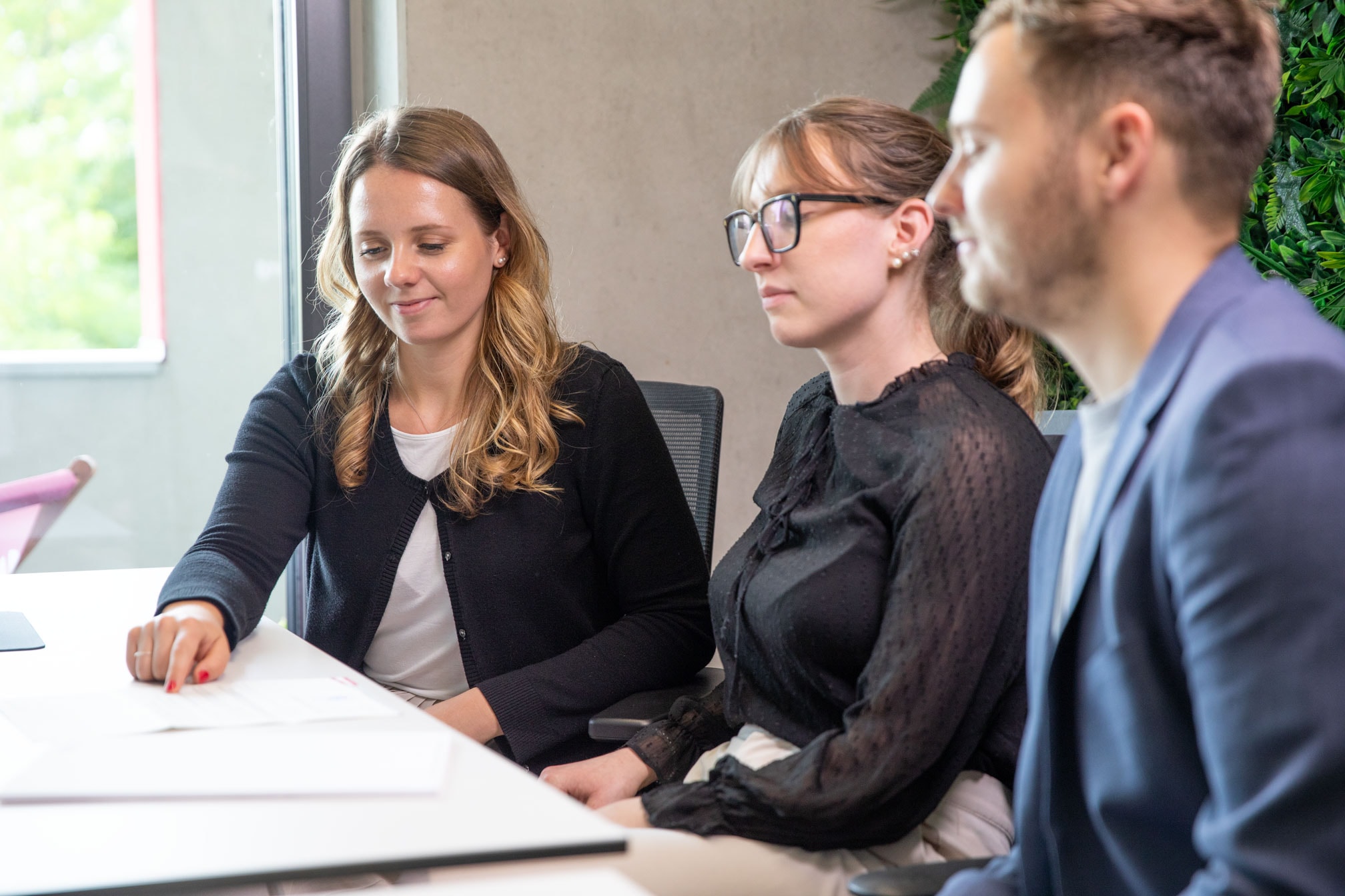 Drei Mitarbeitende im Austausch über strategische Unternehmensdokumente.