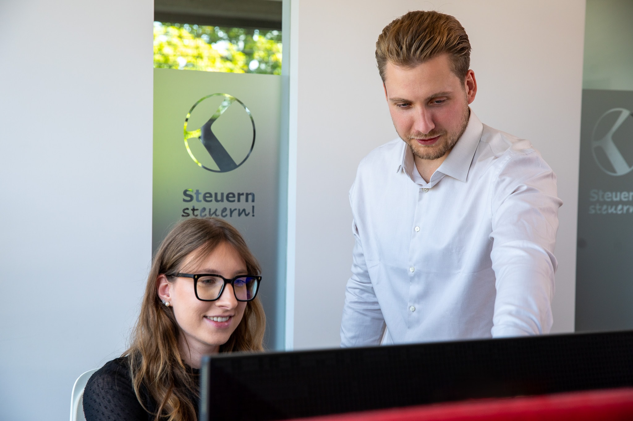 Zwei Kollegen arbeiten gemeinsam an steuerlichen Konzepten zur Vermeidung der Wegzugsbesteuerung.