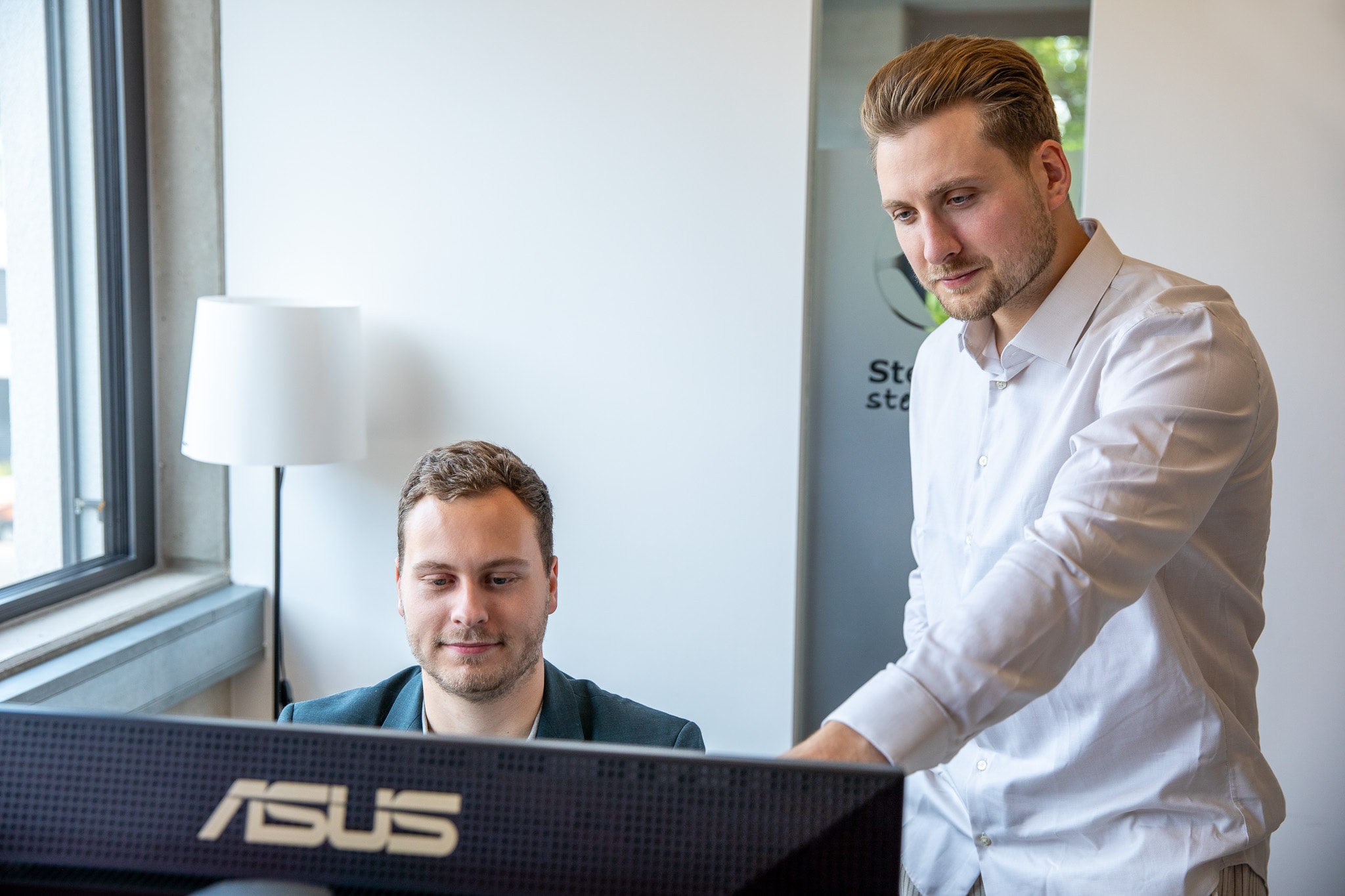 Zwei Kollegen analysieren am Computer steuerliche Optionen zur Gewinnausschüttung einer GmbH.