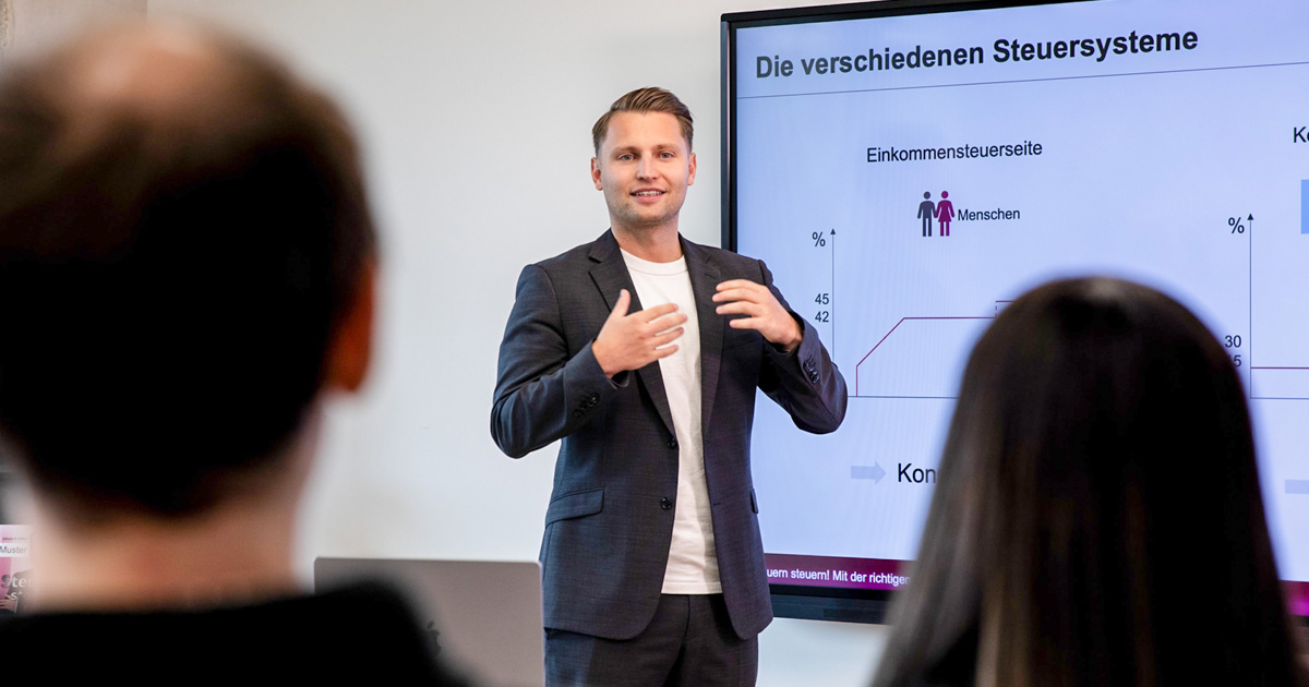 Steuerberater David Kasper erklärt in einer Präsentation die verschiedenen Steuersysteme in dem modernen Besprechungsraum