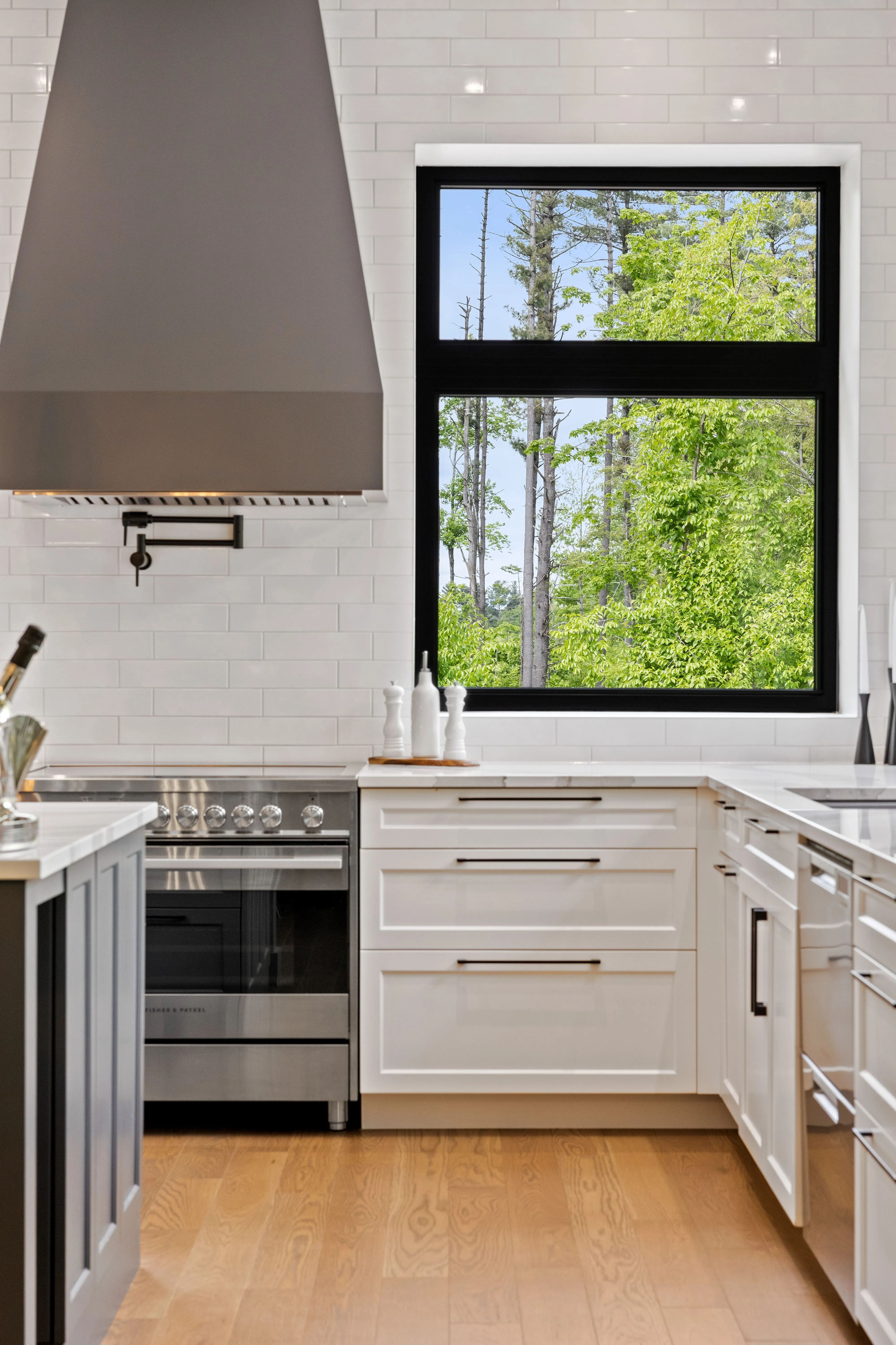 A real estate photography detail shot by Parsell, featuring a modern kitchen with a designer range hood, white subway tile, and a large window, for property marketing in the Ottawa and Montreal regions. | Photo de détail immobilière par Parsell