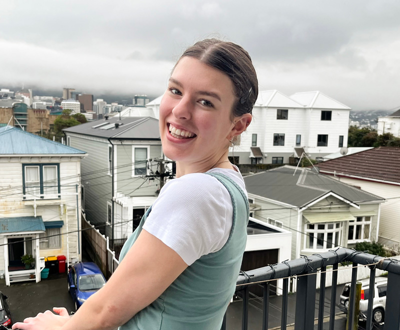 Molly Woodham standing on a balcony overlooking Wellington City.