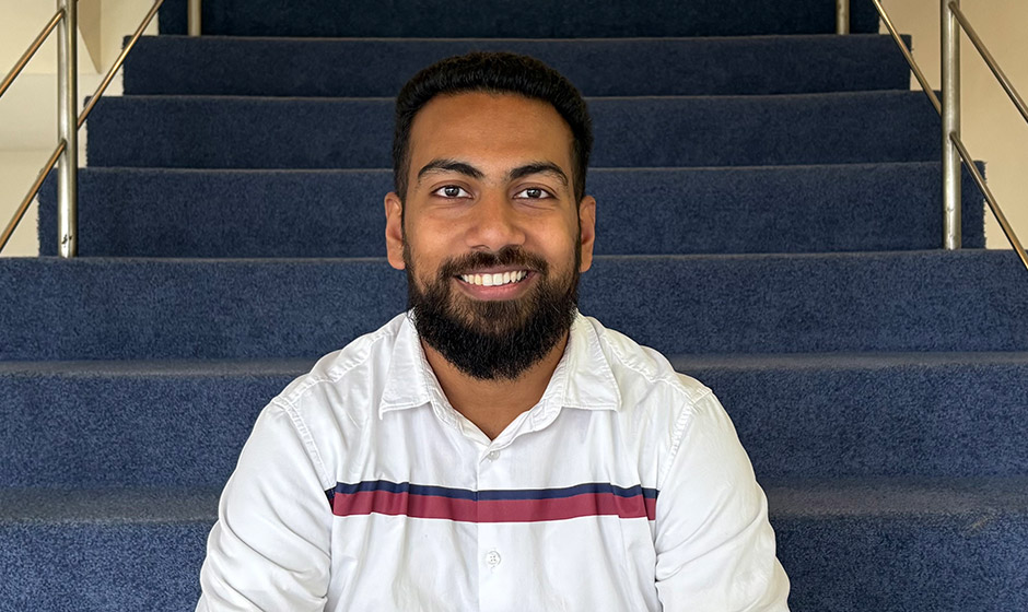Zelzob Kakkat sitting on some blue carpeted stairs.