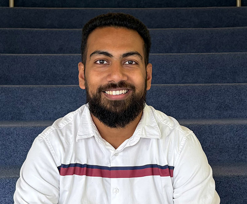 Zelzob Kakkat sitting on some blue carpeted stairs.