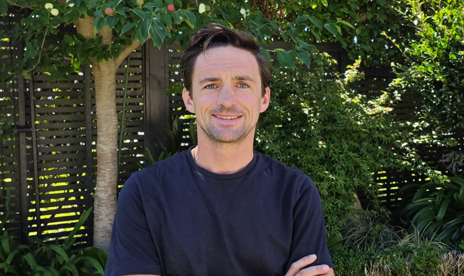 Craig Adolph standing in front of some trees with his arms folded.
