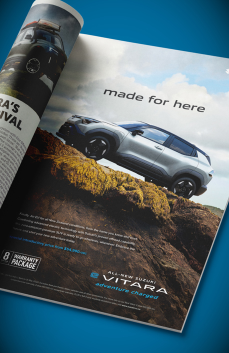A magazine ad featuring a silver Suzuki e Vitara on a steep rocky hill.