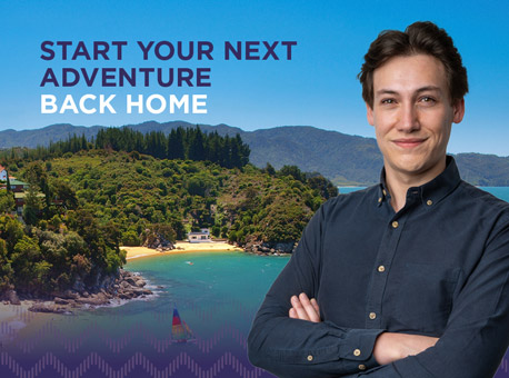 A teacher standing in front of an image of coastal New Zealand with the sea, beach and bush covered headland, with text that says "START YOUR NEXT ADVENTURE BACK HOME".