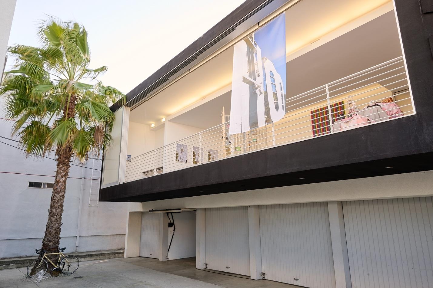 A building with a balcony and palm treesAI-generated content may be incorrect.