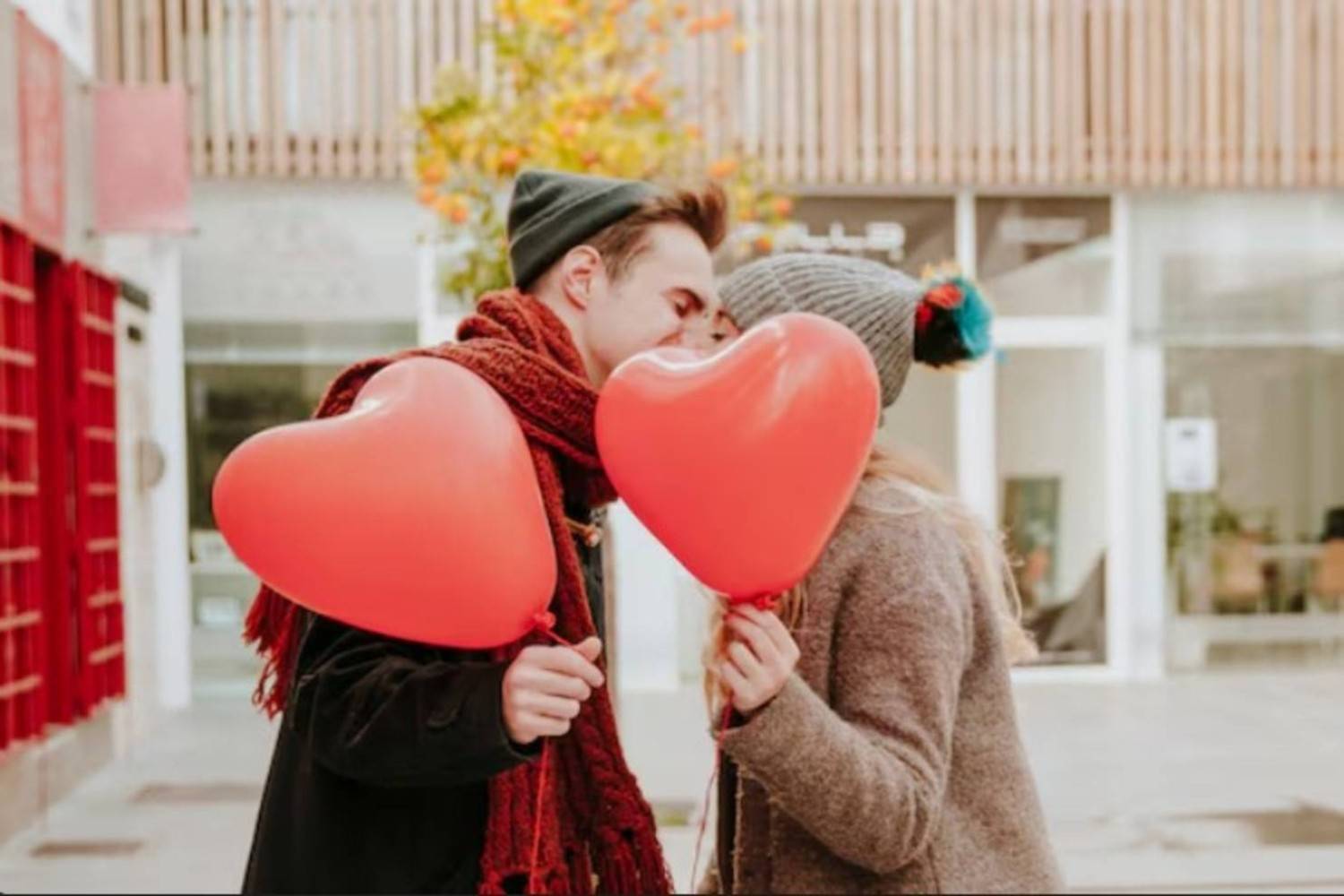 Romantic couple with balloons kissing on street