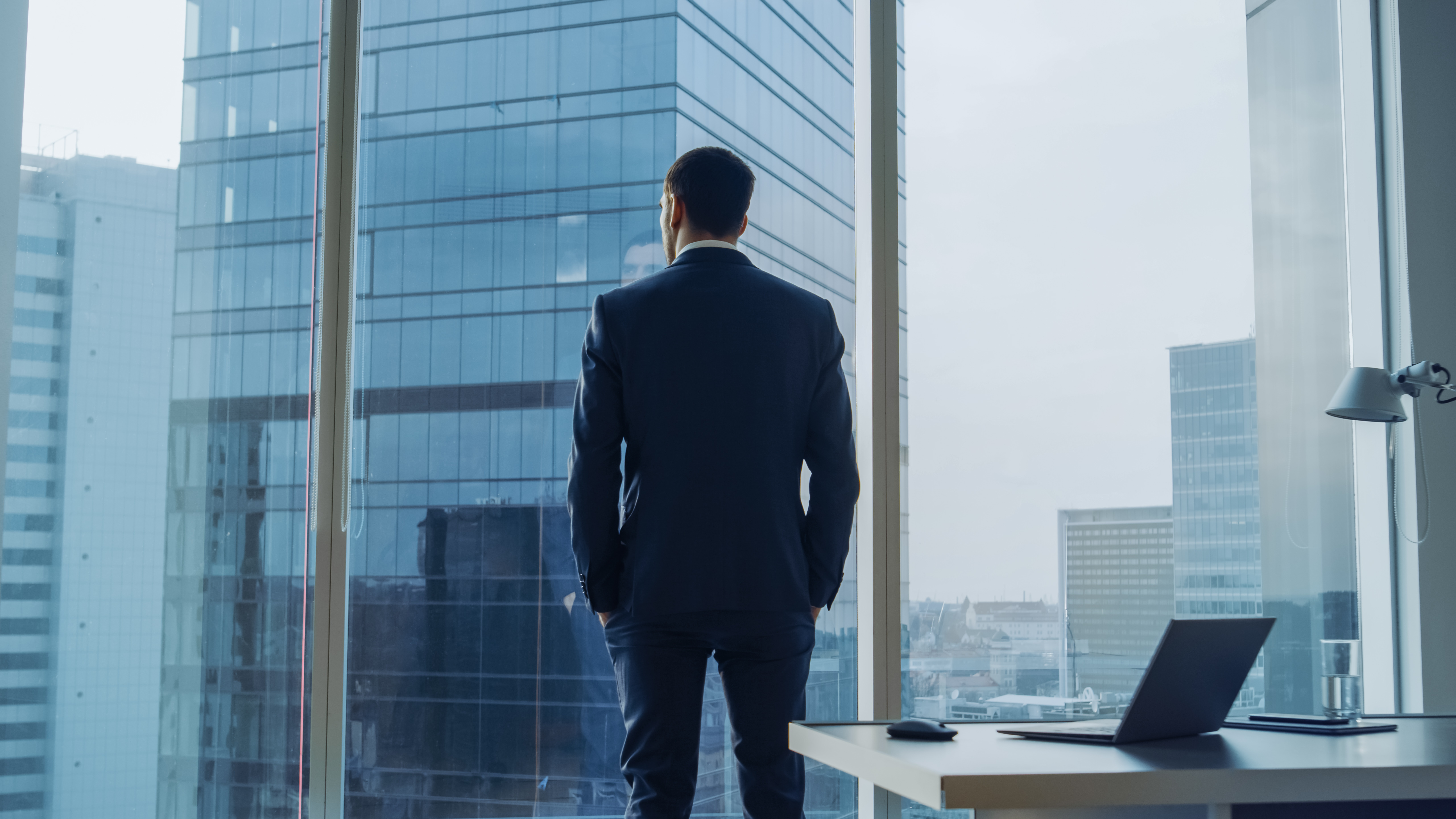 Professional standing in an office overlooking a city skyline, representing the challenges successful professionals face when dating.