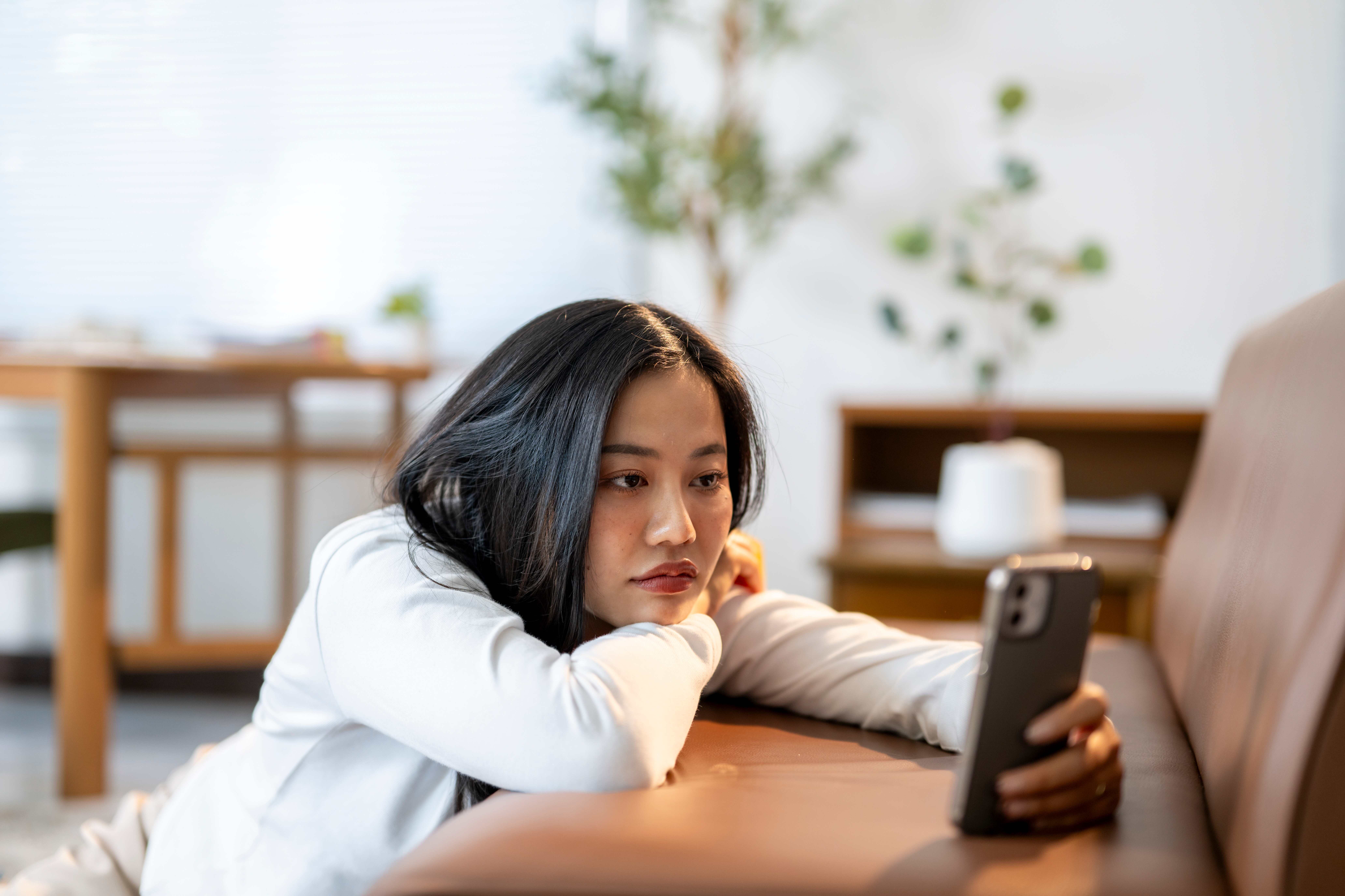 women scrolling on her phone while bored