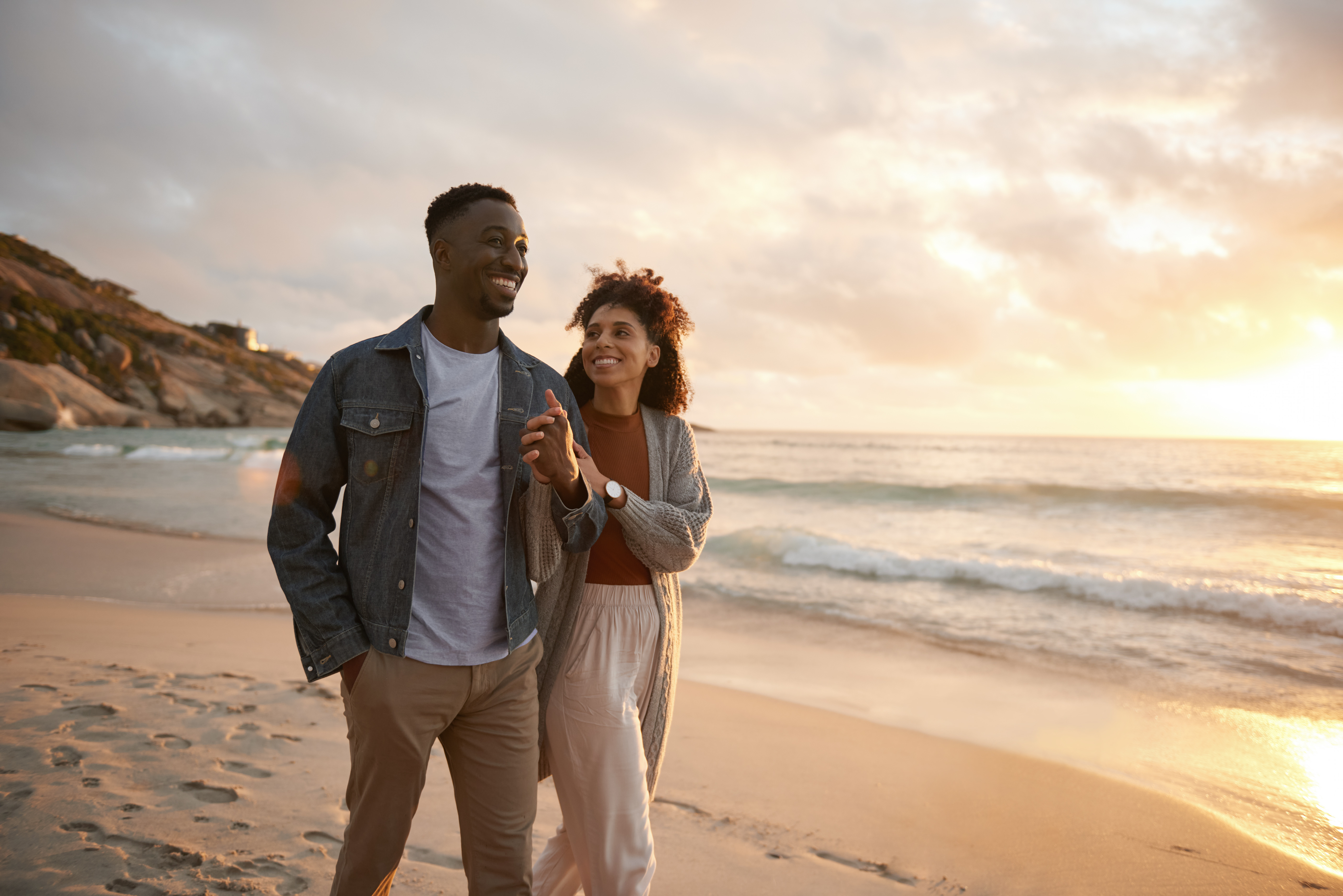 Couple walking together on the beach at sunset and enjoying time together