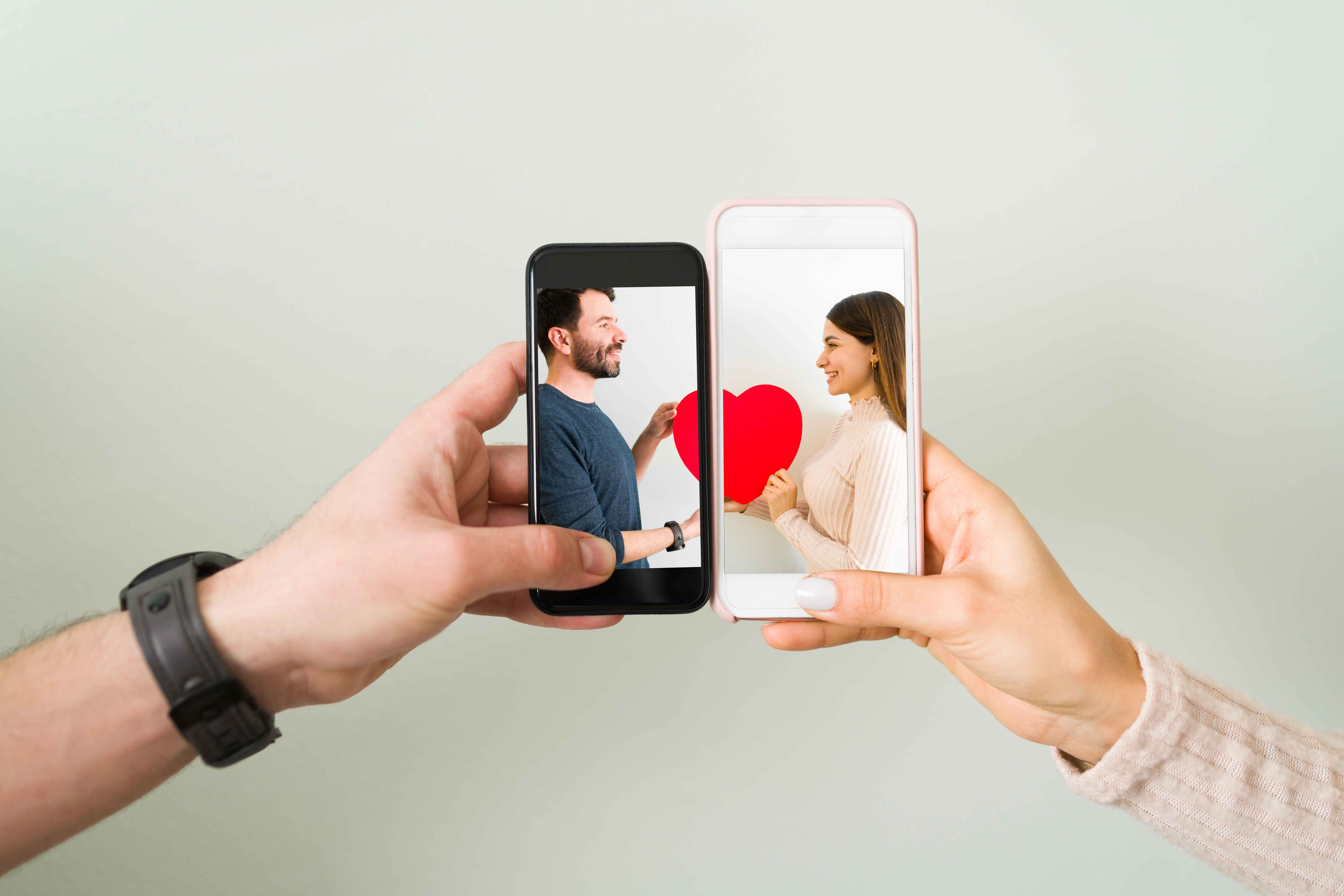 Two hands holding phones facing each other with a red heart icon glowing between the screens