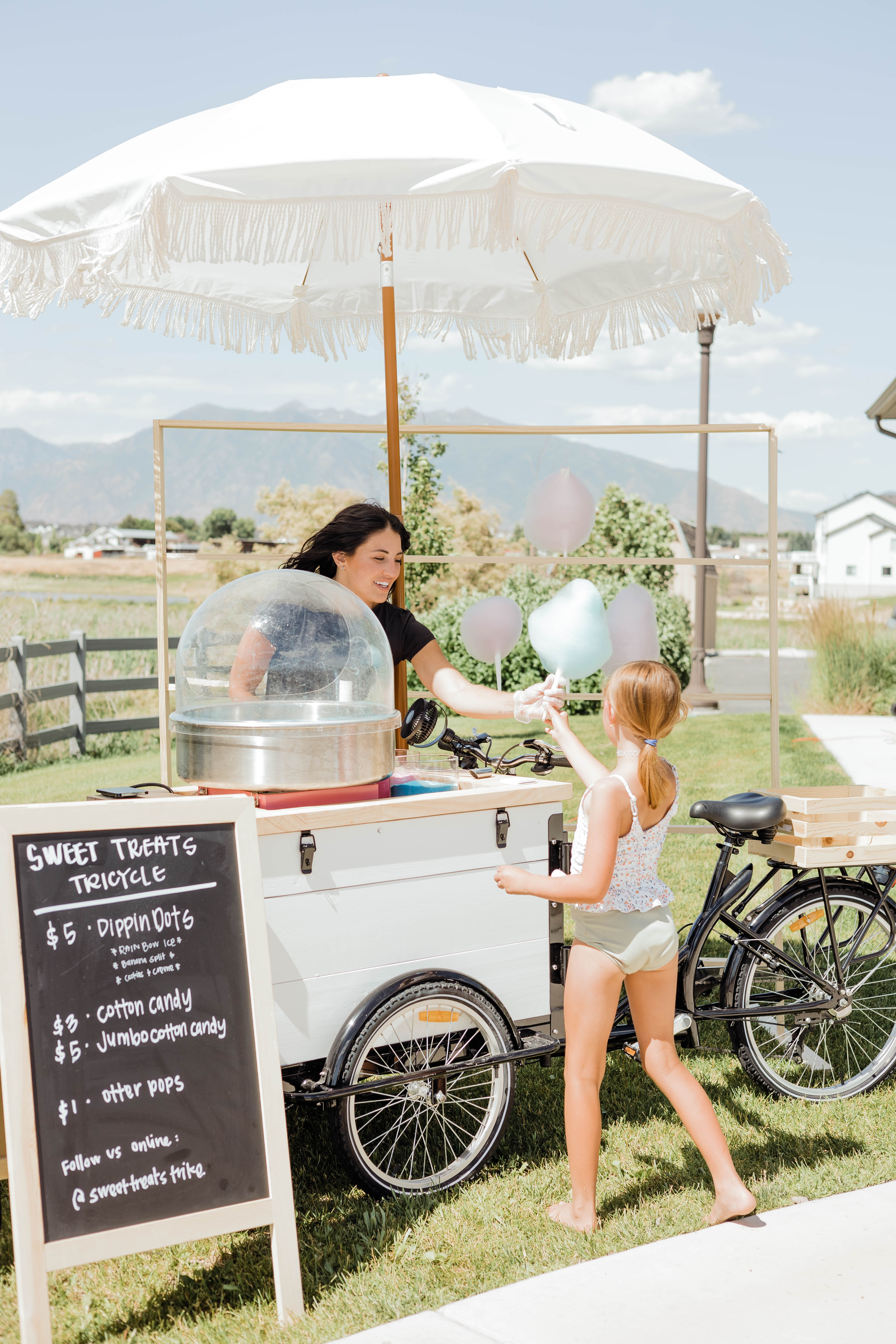 Sweet Treats Trike employee handing cotton candy to a child at Utah event
