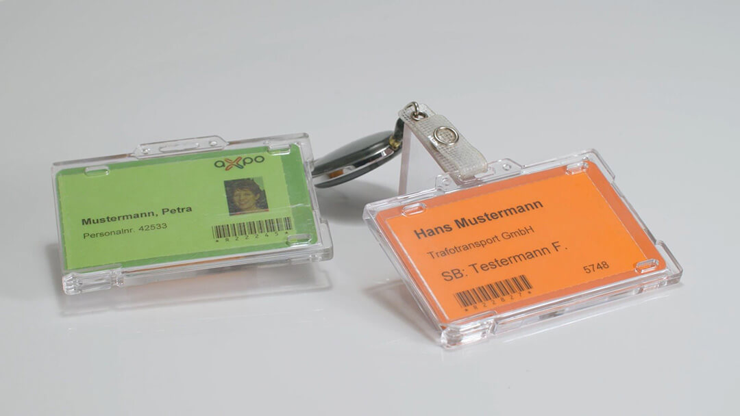 Zwei Mitarbeiterausweise in Plastikhüllen, einer grün, einer orange.
