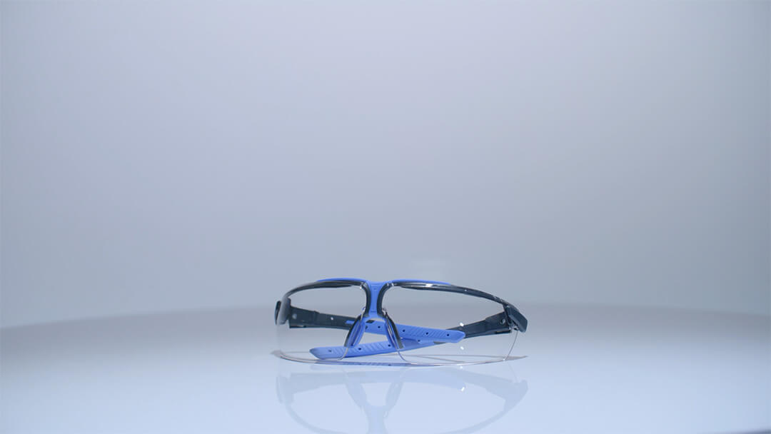 Schutzbrille mit klarem Glas und blau-schwarzem Rahmen.