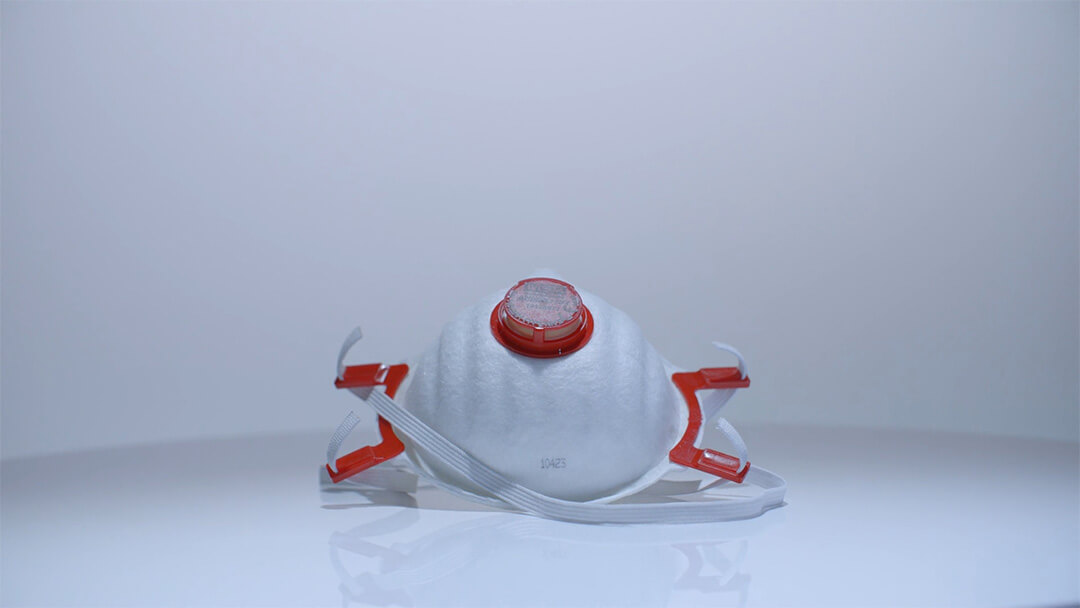 Weisse Atemschutzmaske mit rotem Ventil und elastischen Bändern.