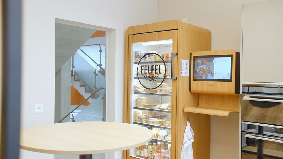 Moderne Küche mit rundem Holztisch und beleuchtetem Kühlschrank von Felfel mit Touchscreen.