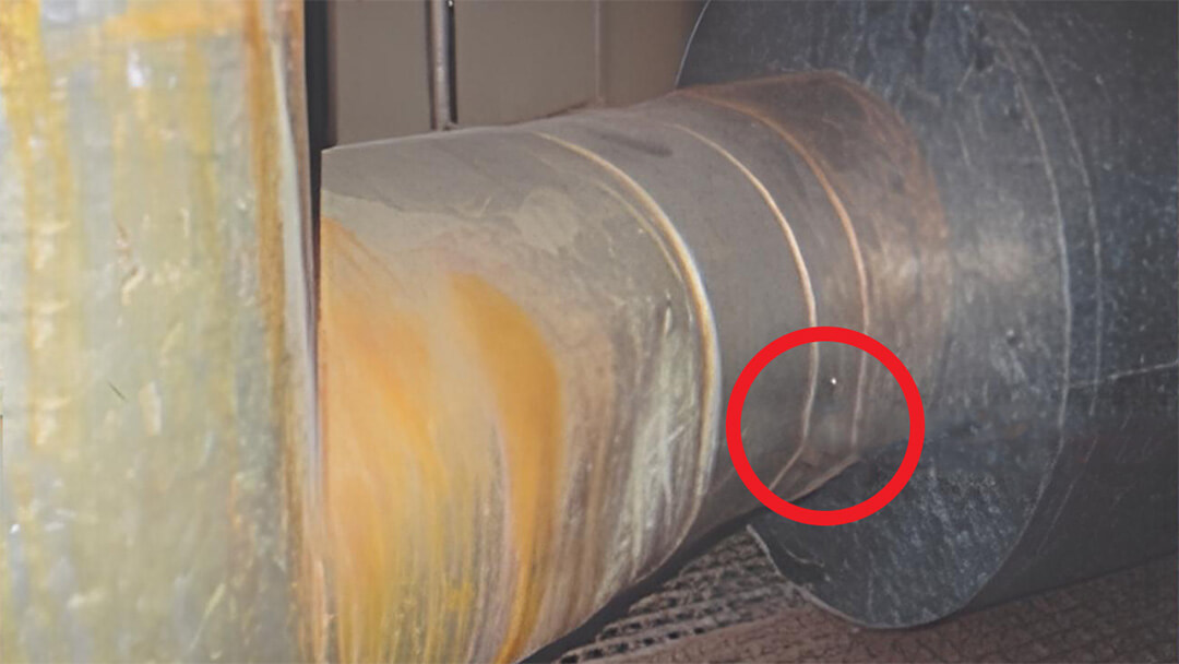 Isolation. Nahaufnahme einer abgenutzten Metallwelle mit rotem Kreis zur Markierung eines Details.