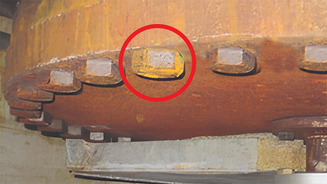 Korrosion. Nahaufnahme einer verrosteten Metallflanschverbindung mit Bolzen, einer markiert mit rotem Kreis.