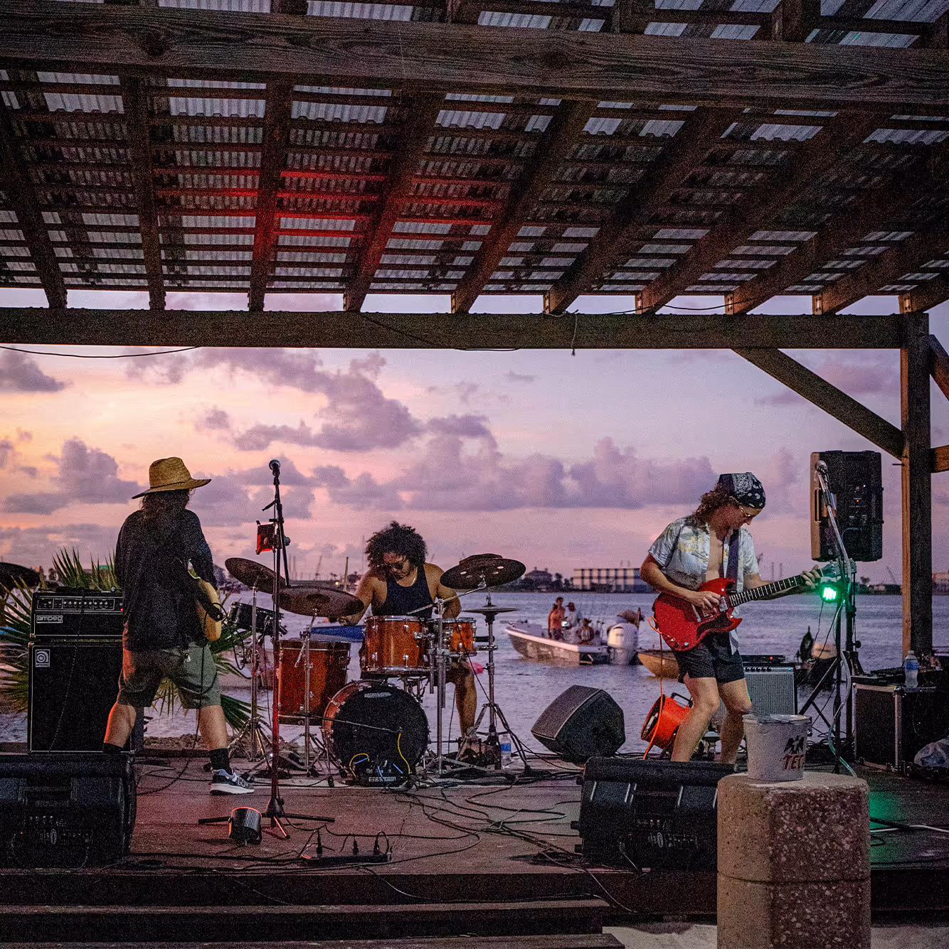 Band peforming on a stage with the water and sunset in the background in Galveston, Texas