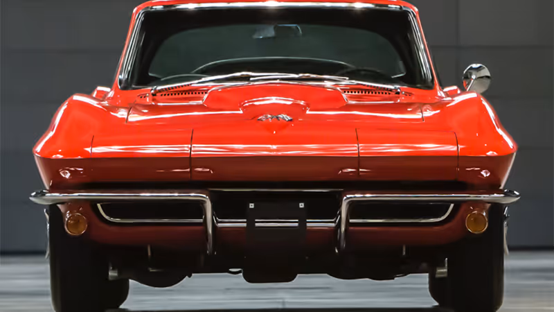 A vibrant red vintage car with a sleek, angular design is the focal point of the image, set against a dark, minimalist background.

