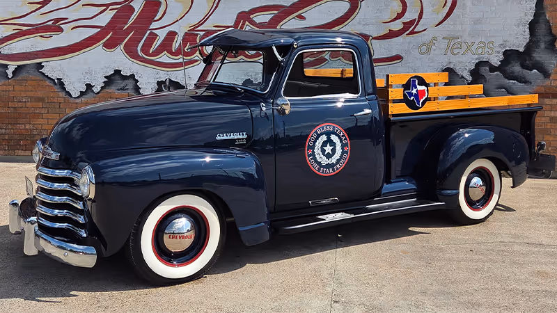 A vintage black pickup truck with a distinctive logo and design, parked in front of a colorful mural depicting the state of Texas.

Galveston, Texas Moody Gardens 