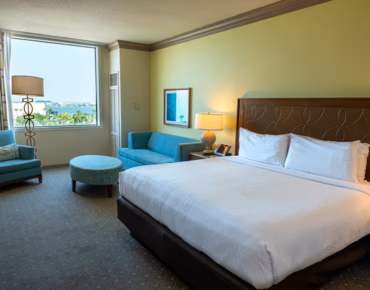 A spacious and well-appointed hotel room with a large bed, a comfortable seating area, and a window offering a scenic view of the surrounding landscape.