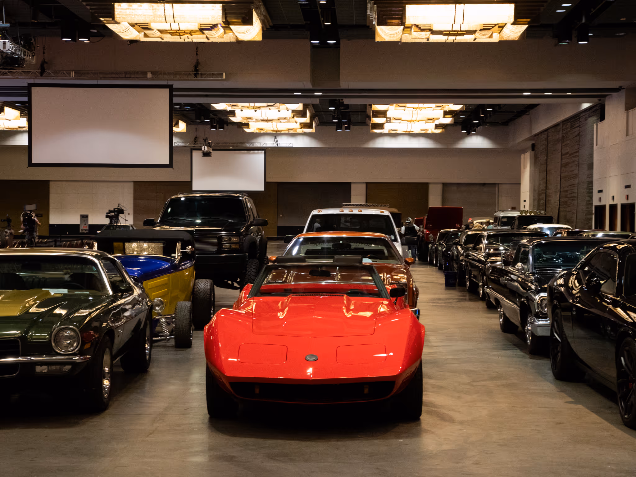 Bright red sports car displayed in a showroom among vintage automobiles