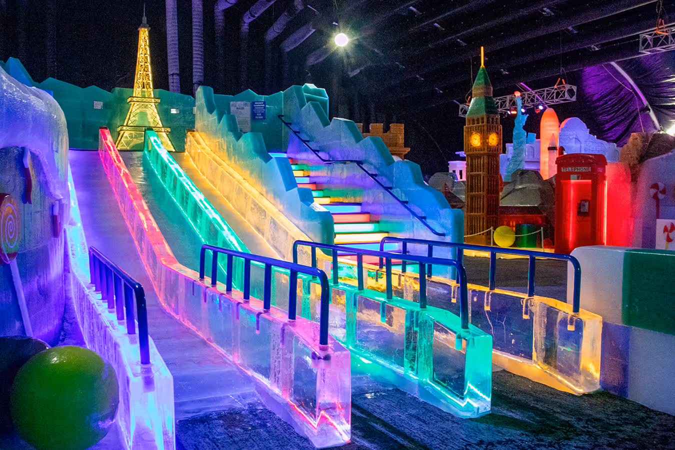 An ice sculputure with the words 'Moody Gardens ICE LAND Pole-to-Pole' carved in ice on an ice blue wall. Two ice carved polar bears are looking at the words. There is a clock that indicates the temperature hanging above the words carved on the wall.