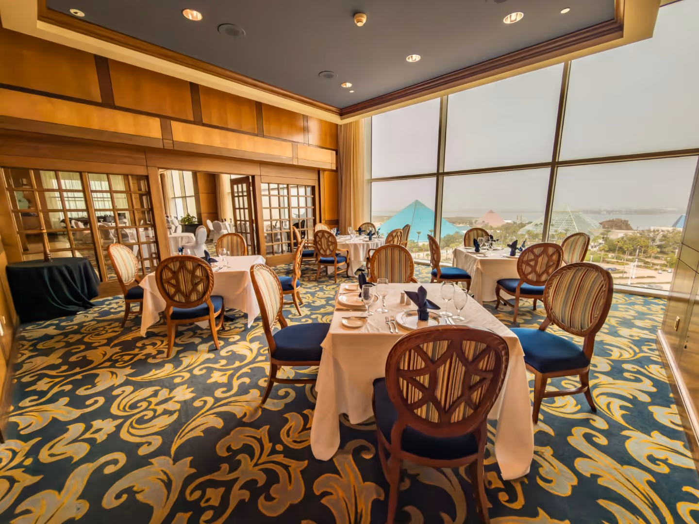 Tables at Shearn's Seafood & Prime Steaks beside windows with a view of the Moody Gardens pyramids