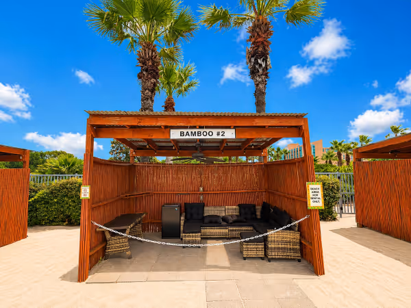 Outdoor bamboo cabana labeled Bamboo #2 with wicker furniture and signs indicating a beach area for rental only.