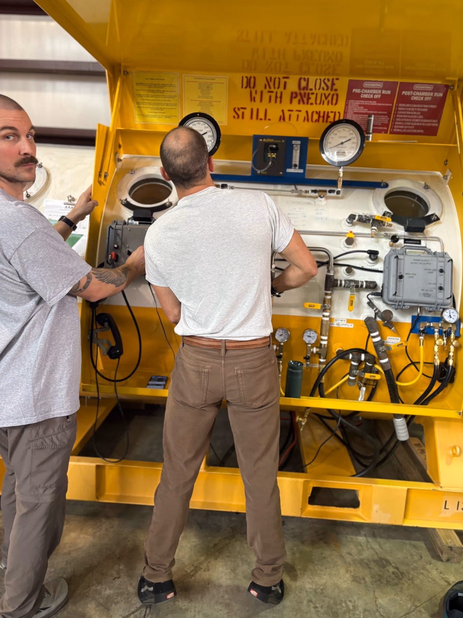 Dive medical technicians operating hyperbaric chamber controls
