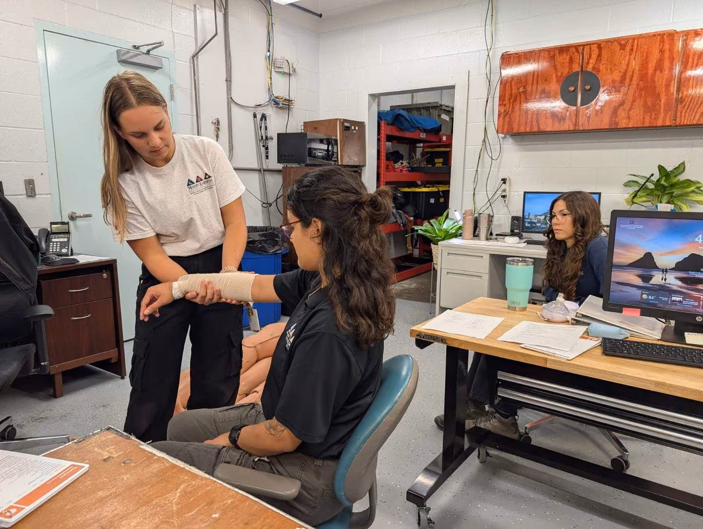 An intern wrapping a wrist brace on a teammate during first aid training