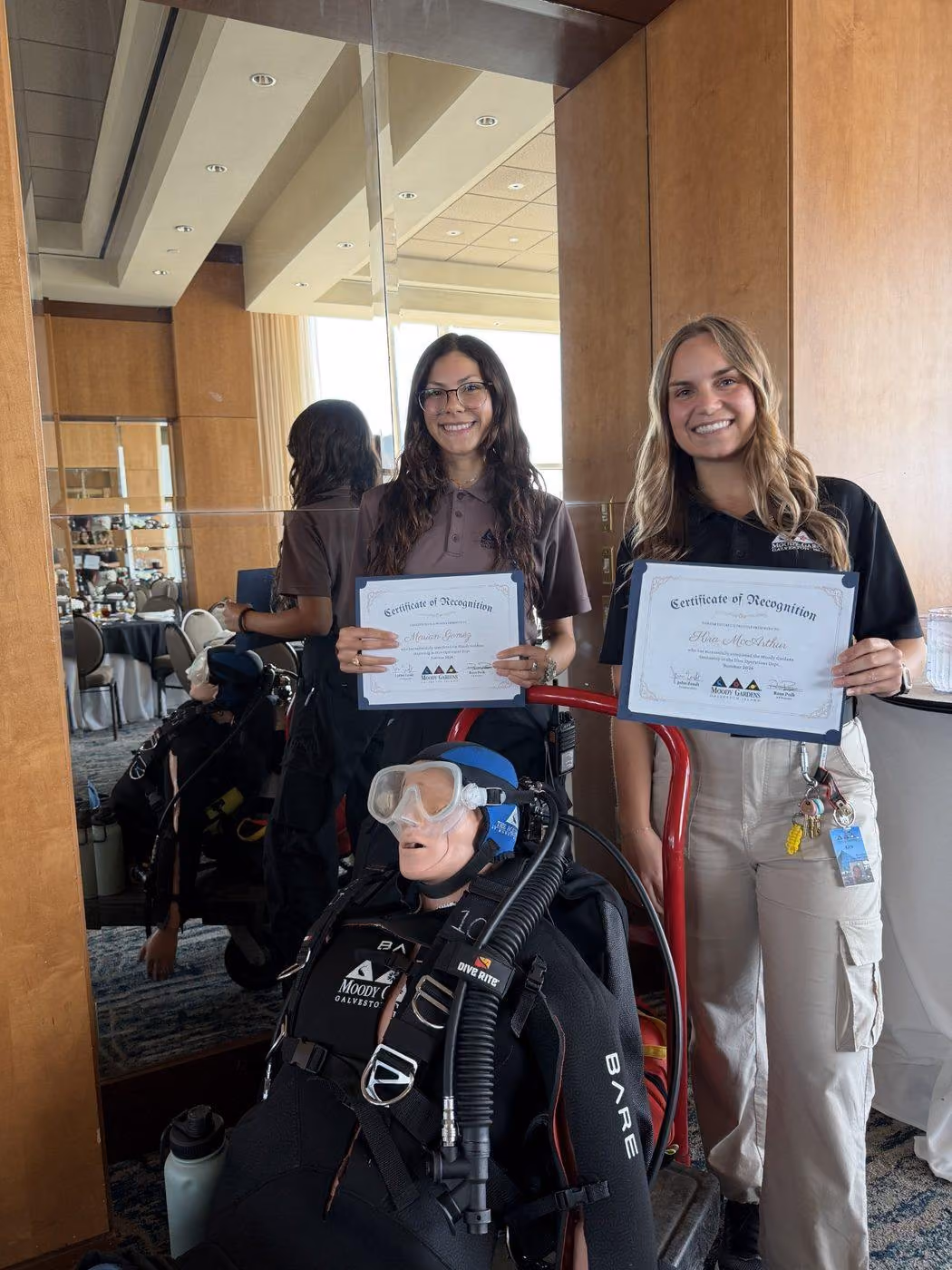 Two interns holding their internship certificates of recognition