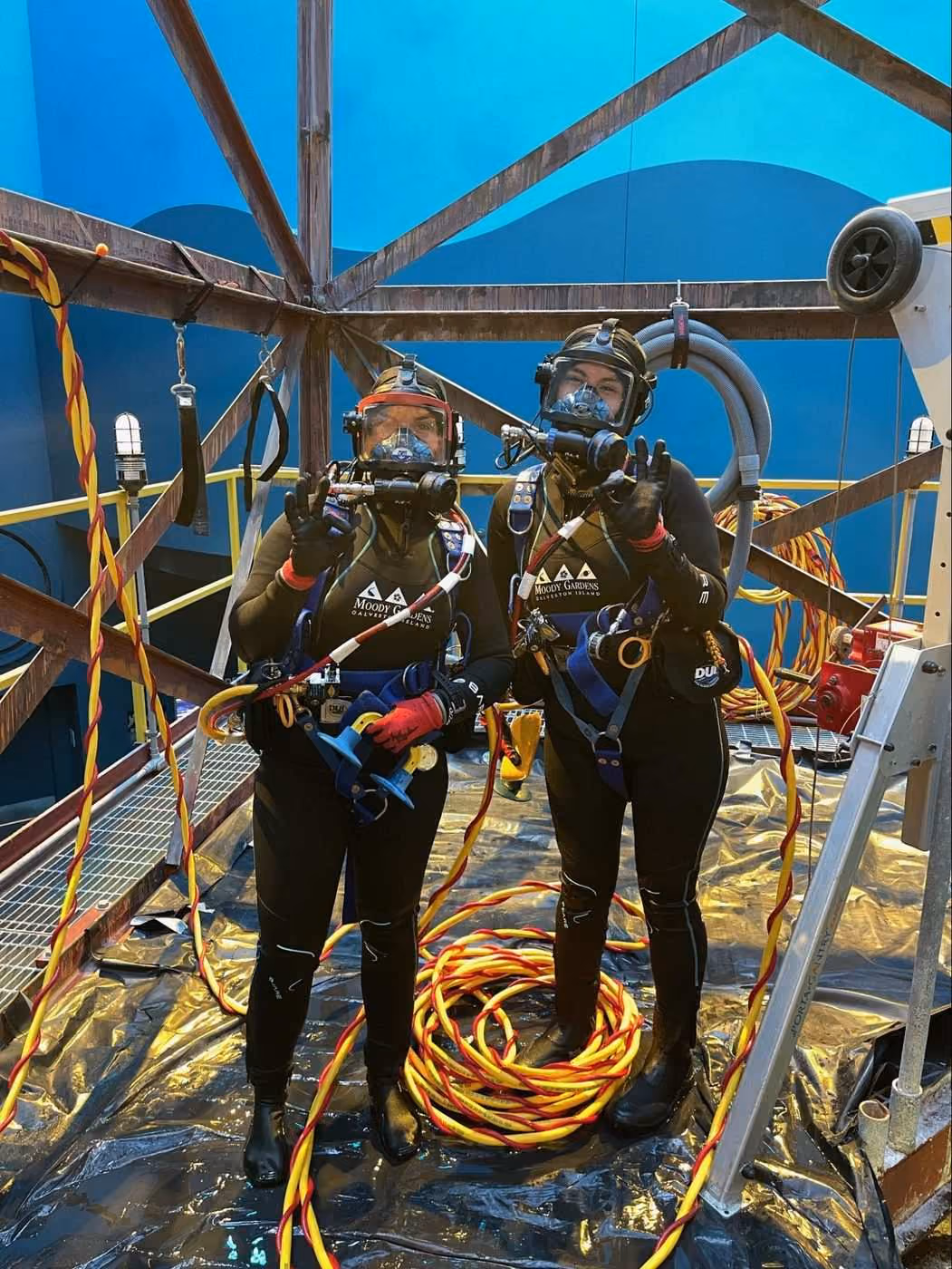 Two interns in surface supply dive gear inside the Rig exhibit