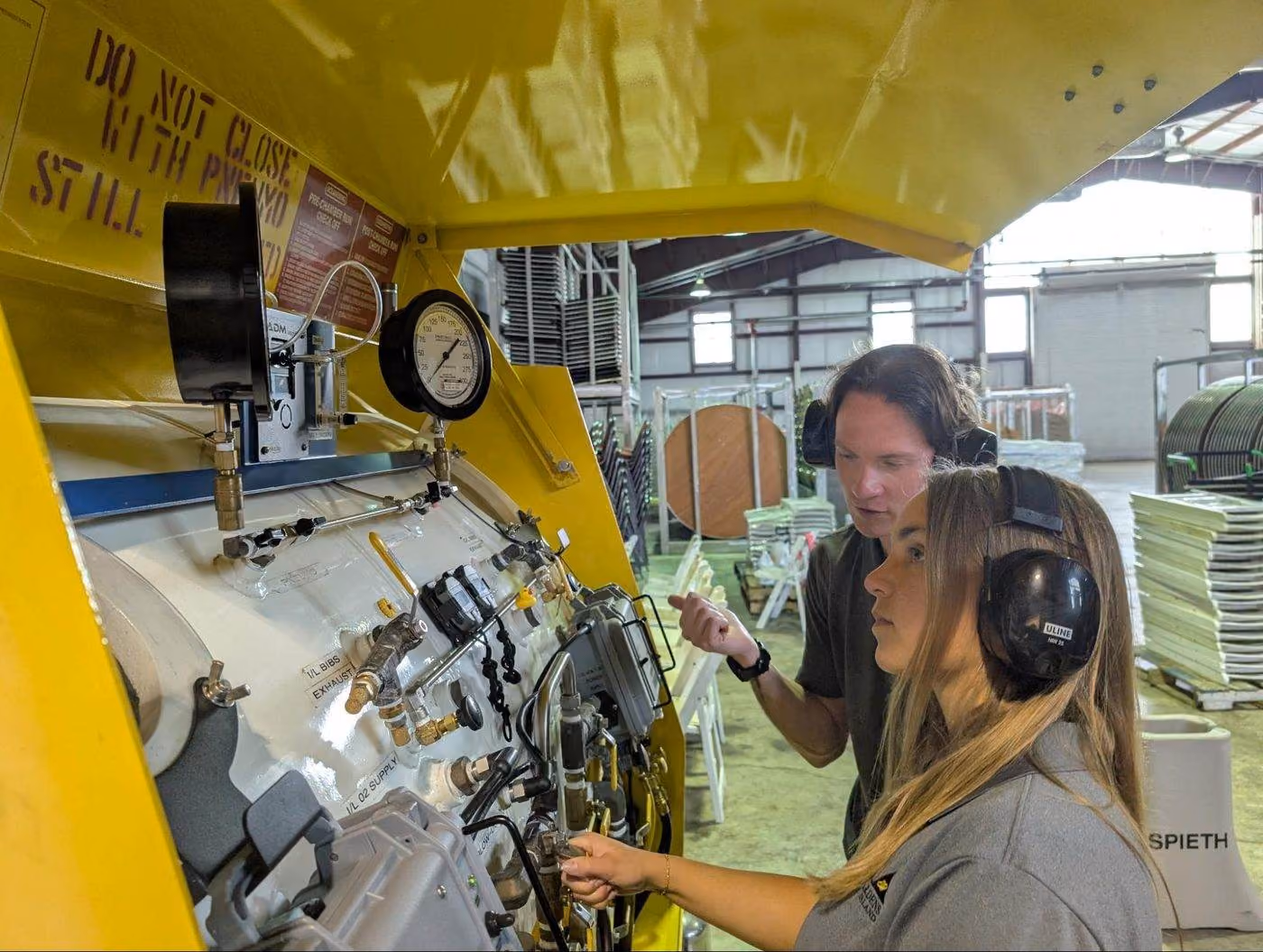 A staff member teaching an intern to operate the hyperbaric chamber controls