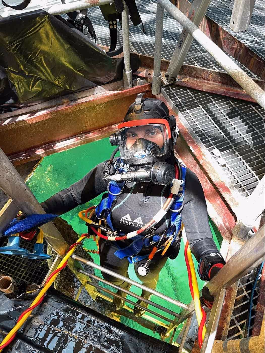 An intern in a full-face mask on the ladder at the Rig exhibit