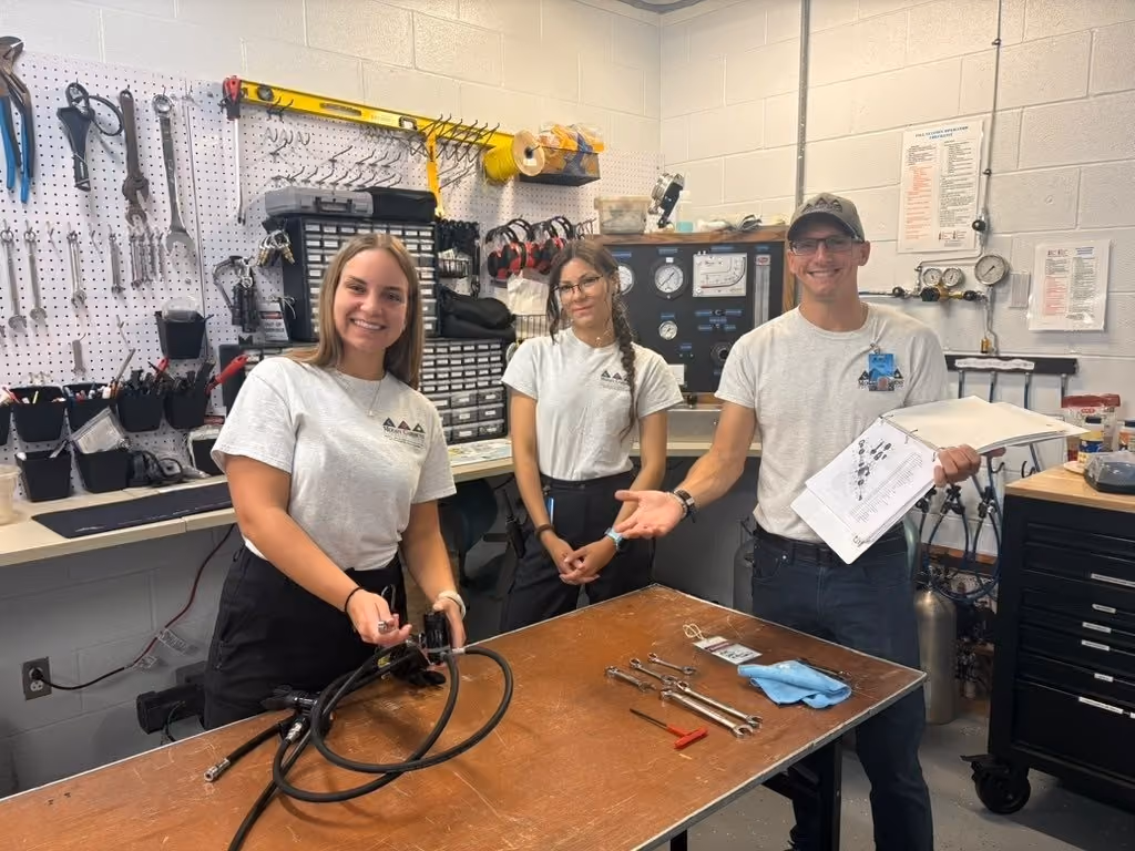 Interns and a staff member at an equipment workbench servicing a regulator