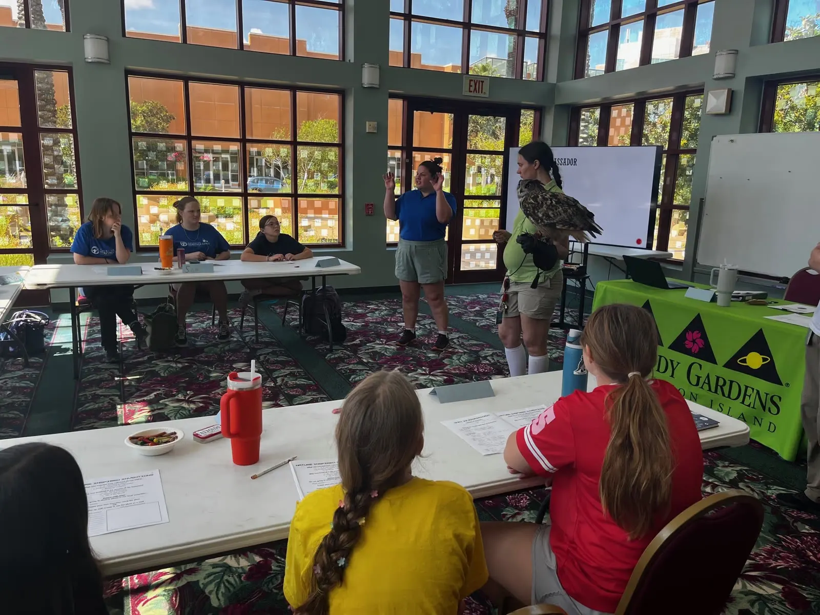American Heritage Girls work through badge activities with a Moody Gardens educator in a sunlit classroom
