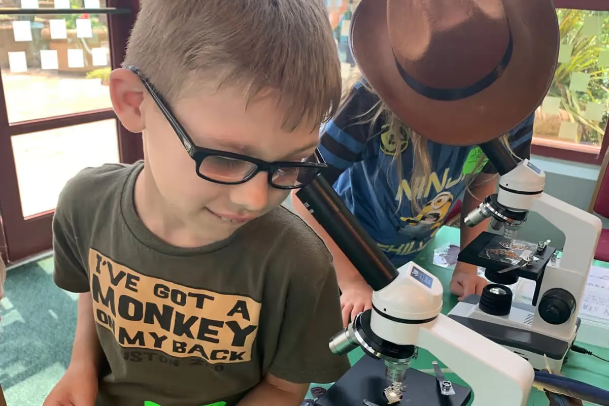 A young student looks through a microscope during a Moody Gardens science lesson