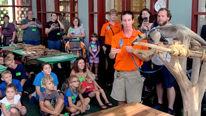 A Moody Gardens educator holds an animal ambassador for a crowd of seated kids
