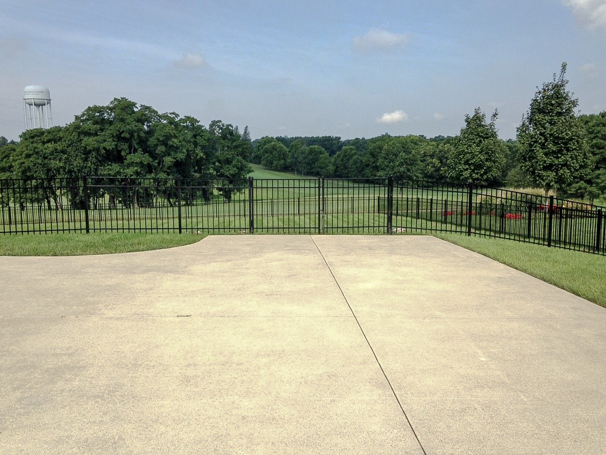 Black aluminum fence and a walk gate beyond a concrete patio in Nicholasville.