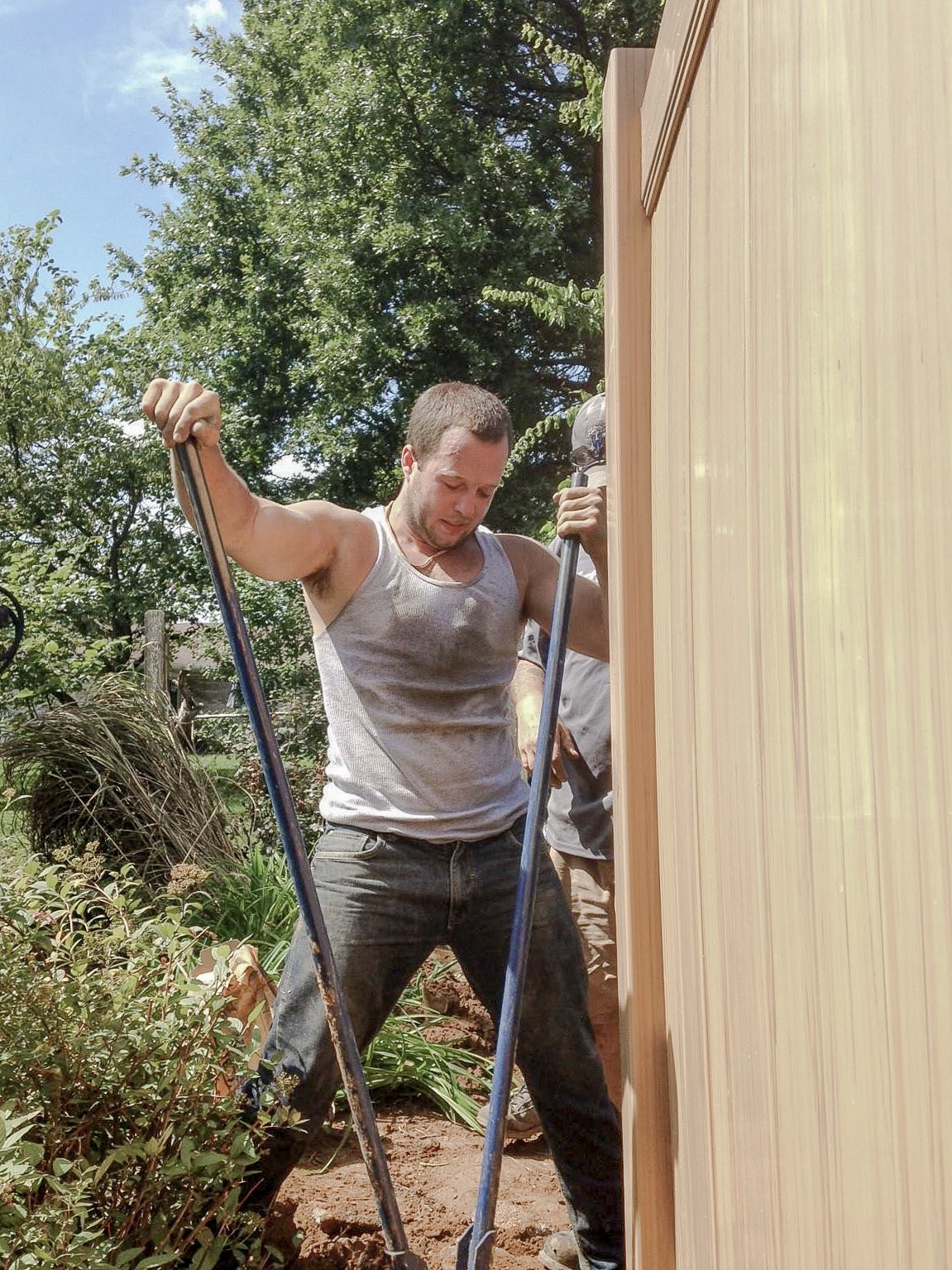 Installer standing beside a vinyl fence panel during work at the post.