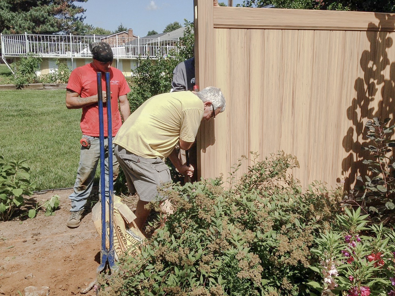 Crew members working beside a vinyl fence post with a level.