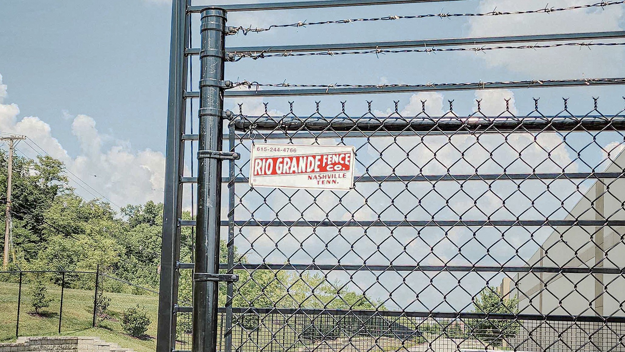 Close view of a black commercial gate frame, chain-link mesh, and Rio Grande sign in Louisville.