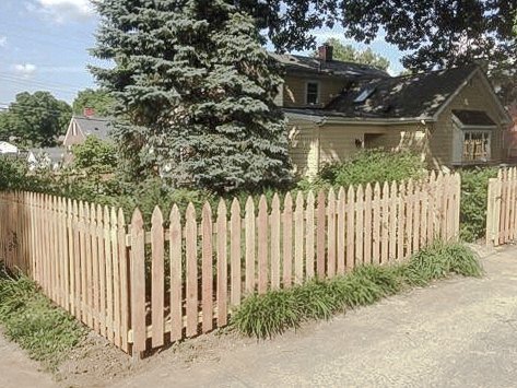 Cedar picket fence turning a corner along a sidewalk at the Midway property.