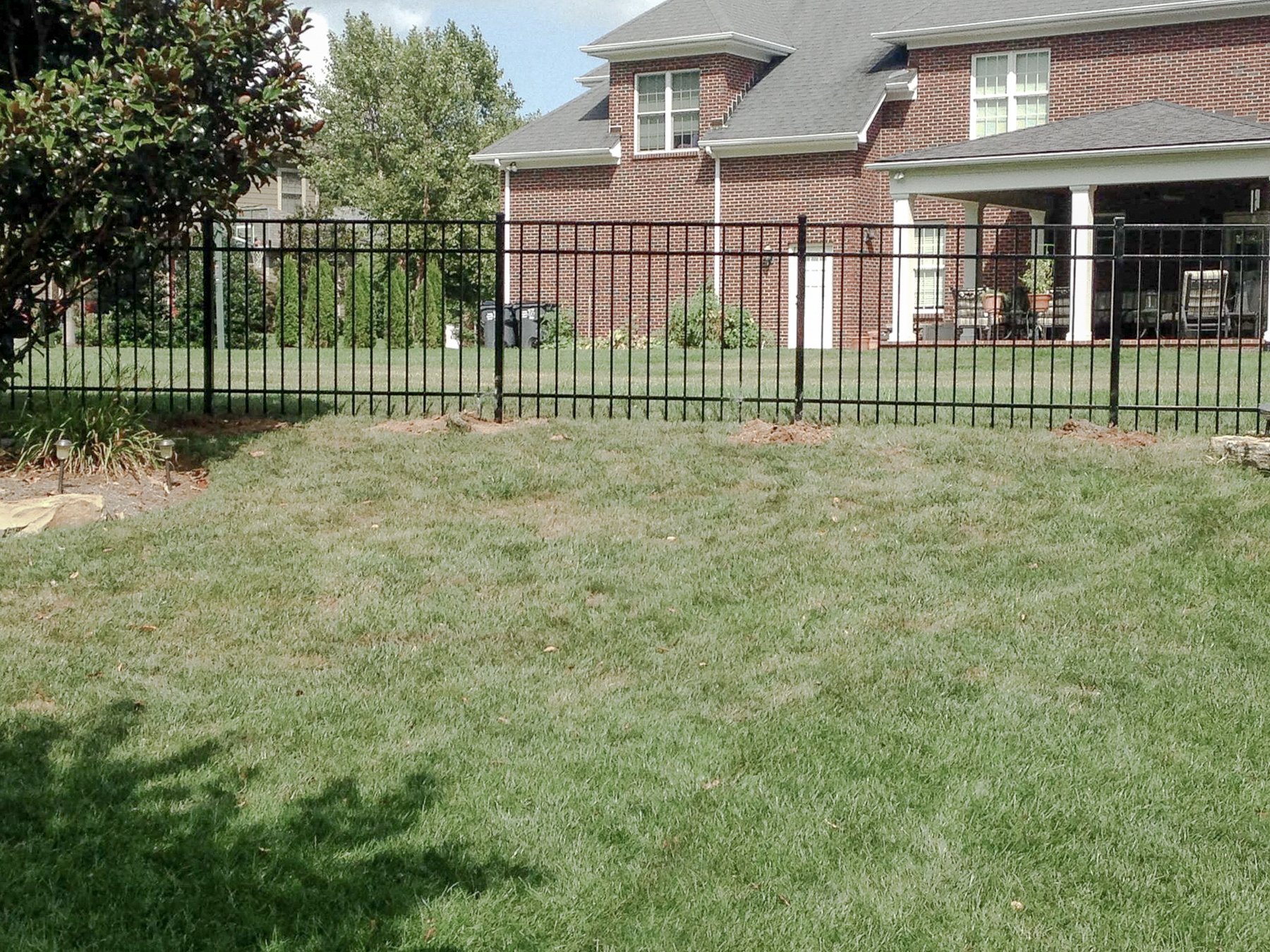 Aluminum fence in front of the brick home and garden on Horse Mint Trail.