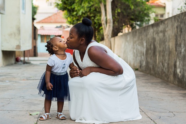 Mother kneeling down to kiss toddler daughter